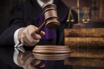 A judge holding up a gavel on top of a table.