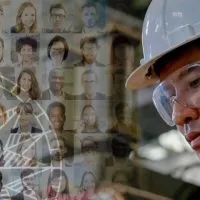 A man in hard hat and goggles looking at faces of people.