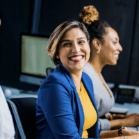 A woman smiles while sitting in front of two other women.