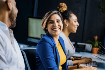 A woman smiles while sitting in front of two other women.