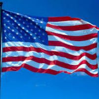 A flag flying in the wind on top of a pole.