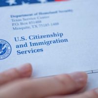 A person holding an envelope with the u. S. Citizenship and immigration services logo on it