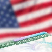 A close up of the green card on top of an american flag.