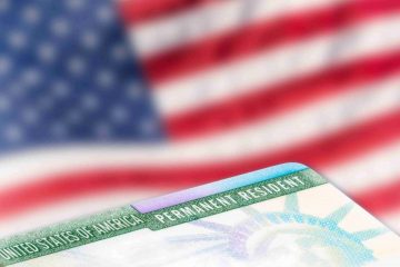 A close up of the green card on top of an american flag.