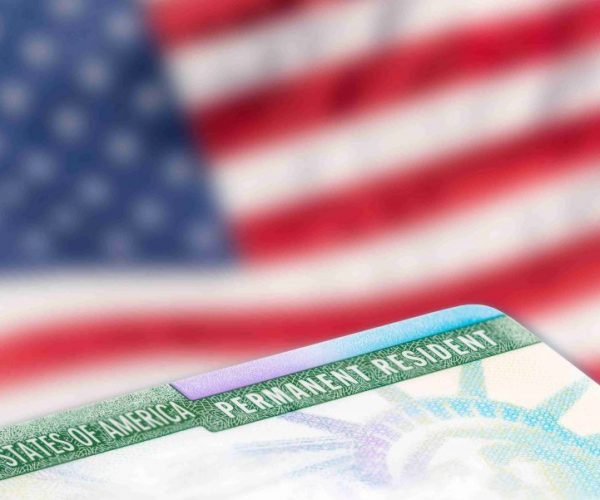 A close up of the green card on top of an american flag.