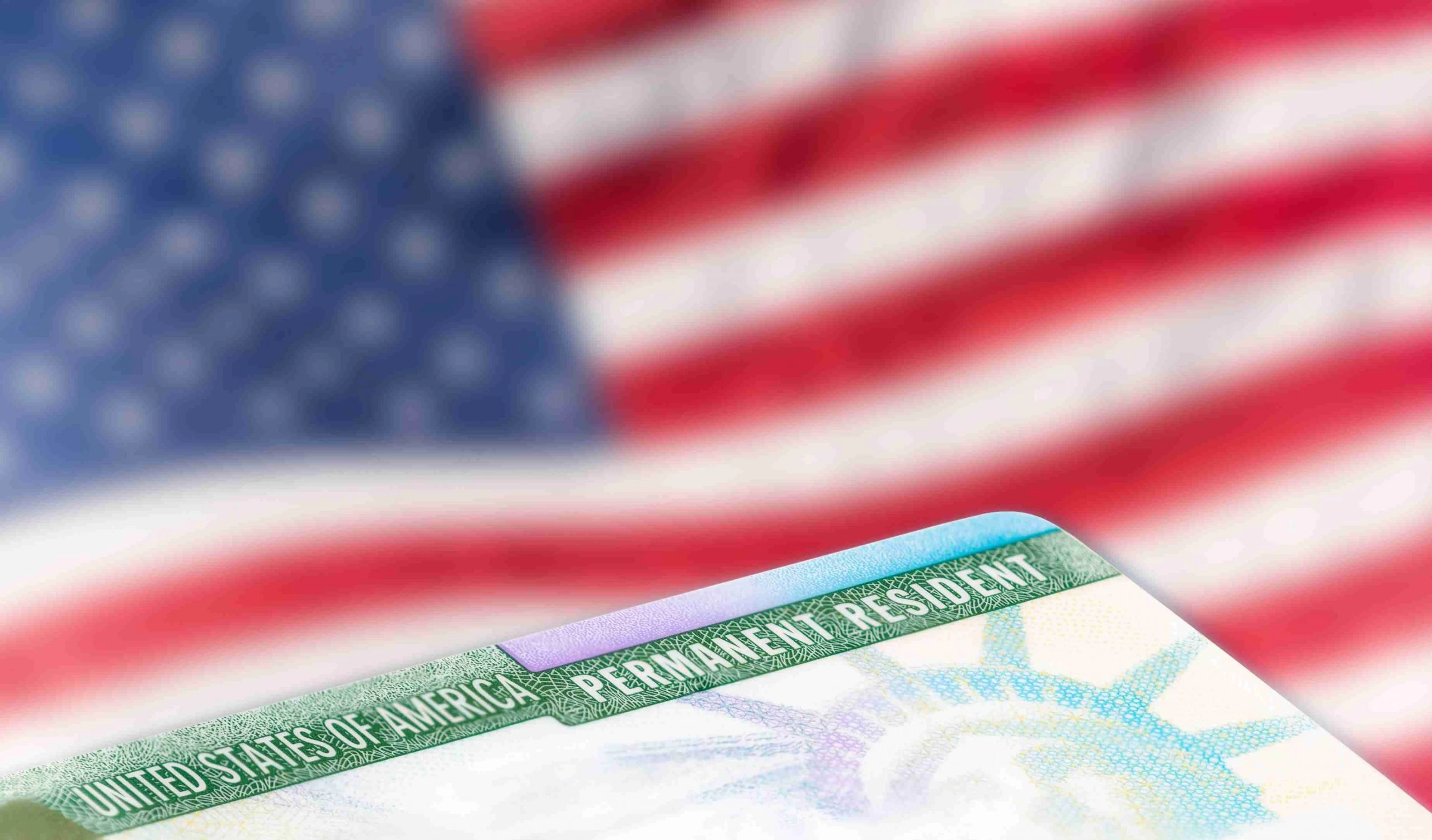 A close up of the green card on top of an american flag. A close up of the green card on top of an american flag.
