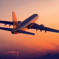 A plane flying in the sky at sunset.