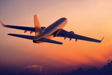 A plane flying in the sky at sunset.