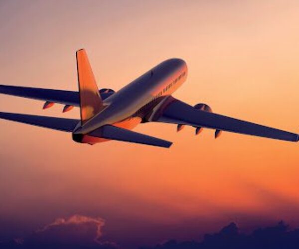 A plane flying in the sky at sunset.