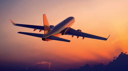 A plane flying in the sky at sunset.