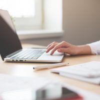 A person typing on a laptop at a desk.