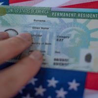 A person holding onto the green card of their permanent resident.