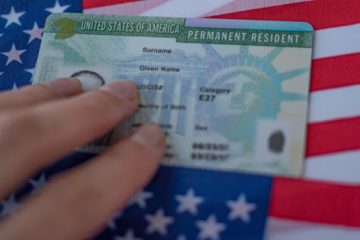 A person holding onto the green card of their permanent resident.