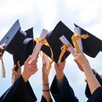 A group of people holding up their graduation hats.