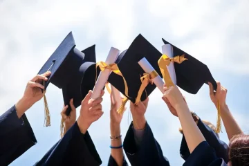 A group of people holding up their graduation hats.