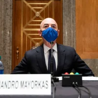 A man with a blue mask sitting at a table.