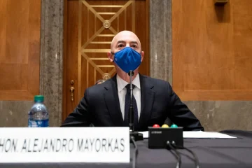 A man with a blue mask sitting at a table.