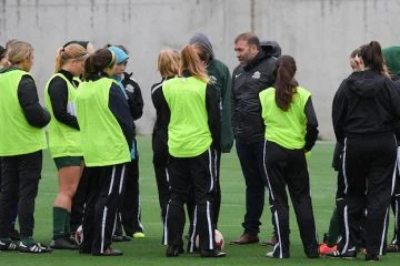 A group of people standing on top of a soccer field.