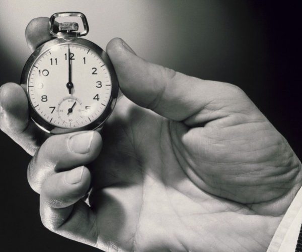 A person holding an old pocket watch in their hand.