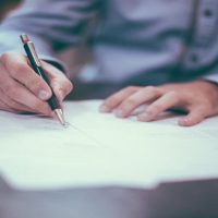 A person writing on paper with a pen.