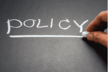 A person writing the word policy on a chalkboard.