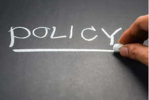 A person writing the word policy on a chalkboard. A person writing the word policy on a chalkboard.