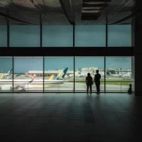 Two people standing in front of a window looking at planes.