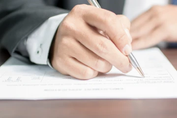 A person in a suit writing on paper
