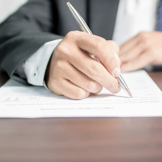 A person in a suit writing on paper
