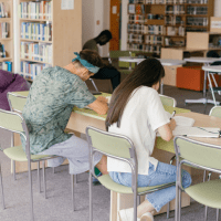 A group of people sitting at tables in a library.