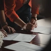 Hands signing contract on wooden table