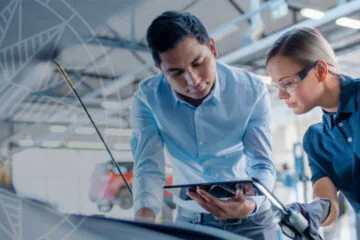 Two professionals collaborating over a tablet in a modern workspace.