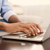 Person typing on a laptop keyboard at a desk.