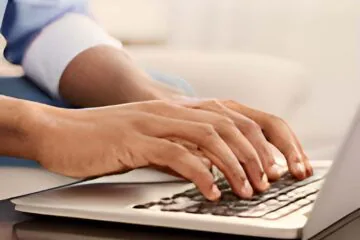 Person typing on a laptop keyboard at a desk.