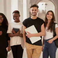 A diverse group of four young adults smiling indoors.