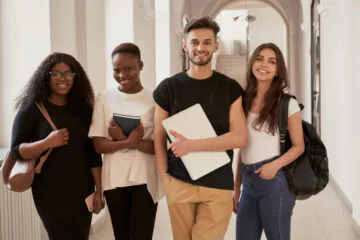 A diverse group of four young adults smiling indoors.